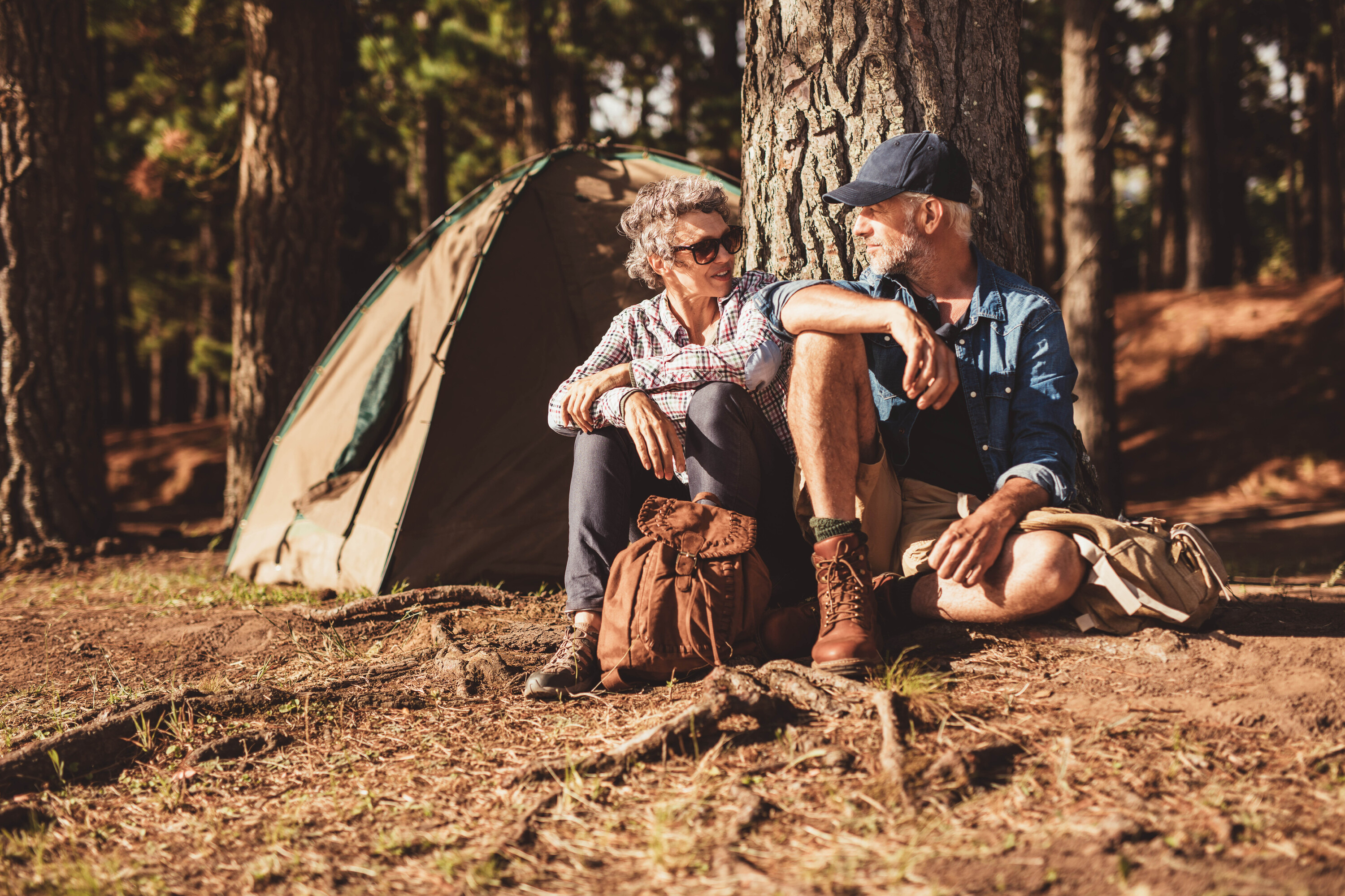Retired couple sitting in front of a tent while camping
